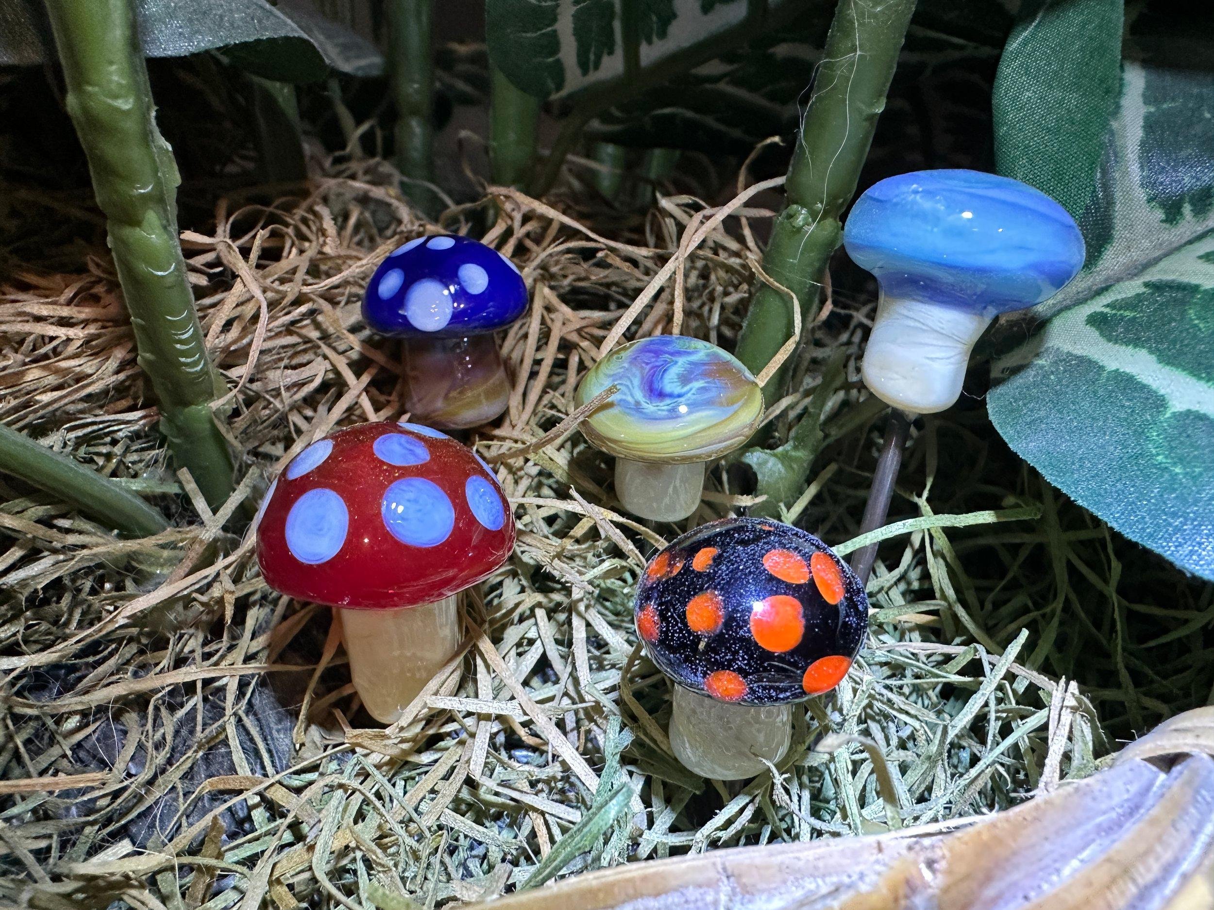 Colorful decorative mushrooms in a nest of dried grass and greenery.
