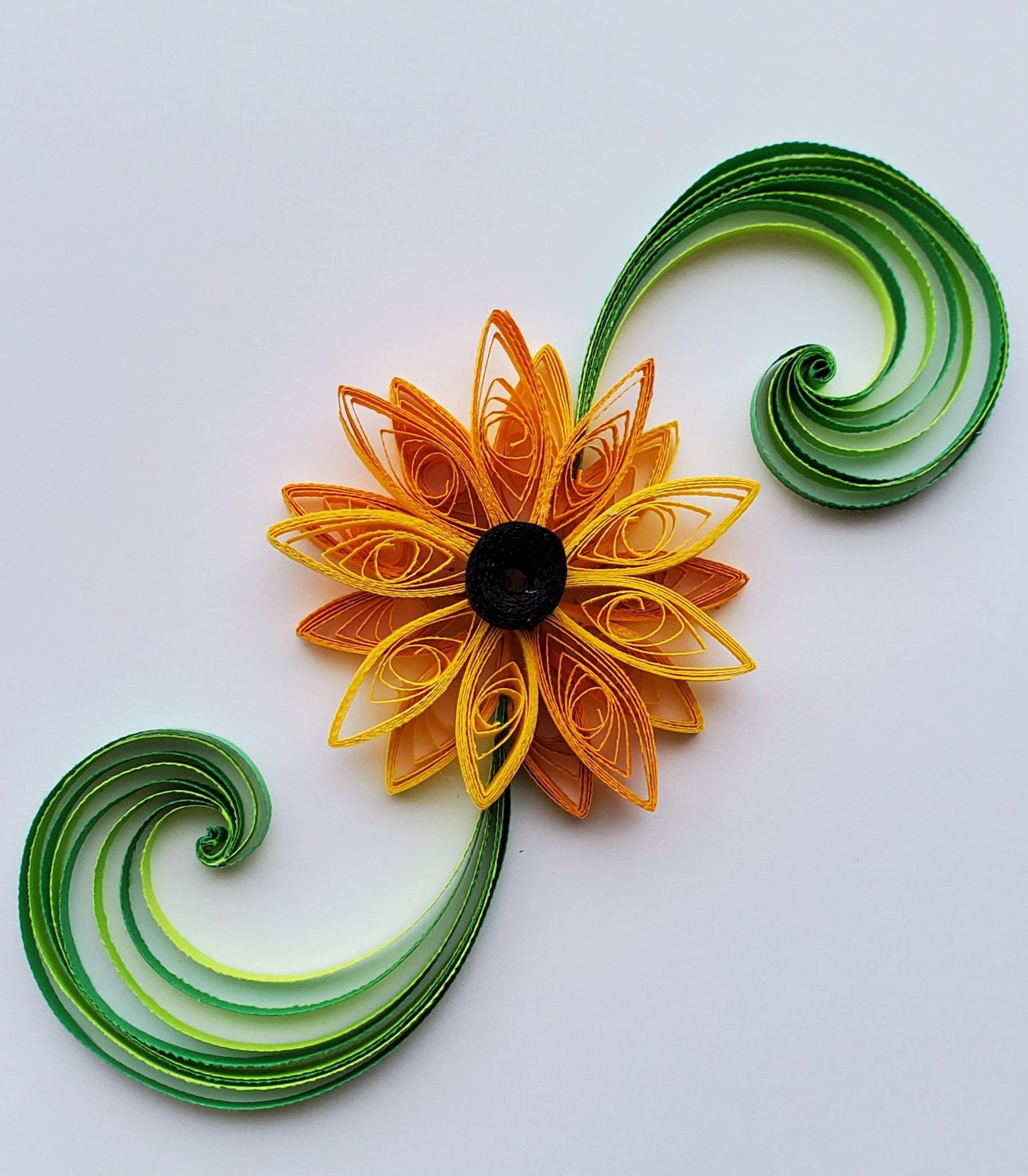 Quilled paper art of a sunflower with green swirling leaves on a white background.